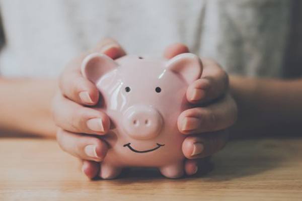 Individual wrapping their hands around a piggy bank