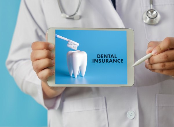 Dentist pointing to dental insurance image on tablet