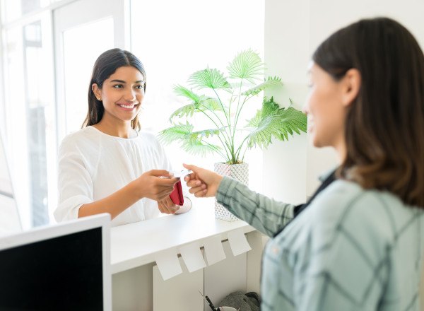 Smiling patient handing receptionist credit card