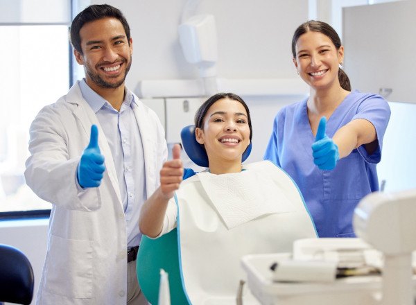 Dentist, dental assistant, and patient giving thumbs up