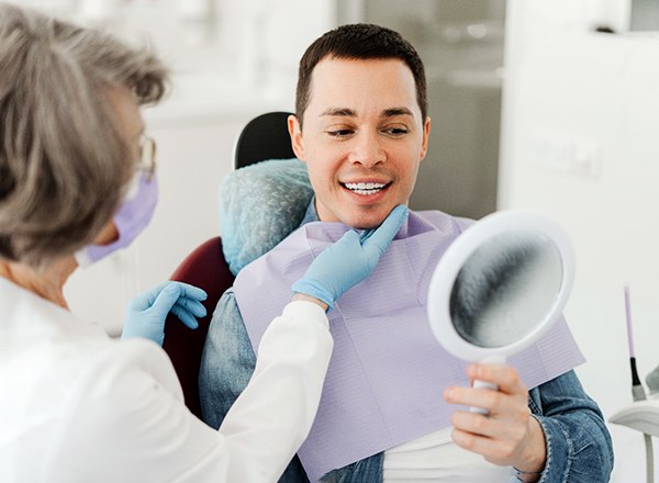 Man smiling at reflection in mirror with dentist