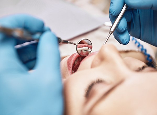 Dentist examining smiling patient's teeth