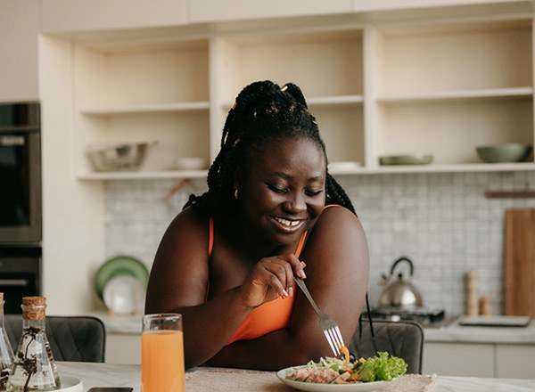 Woman smiling while eating healthy dinner at home