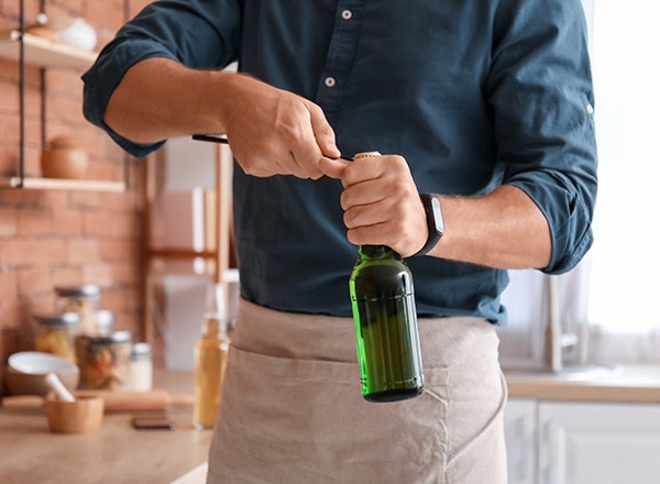 Man with apron using bottle cap opener