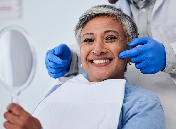 Woman smiling while holding handheld mirror